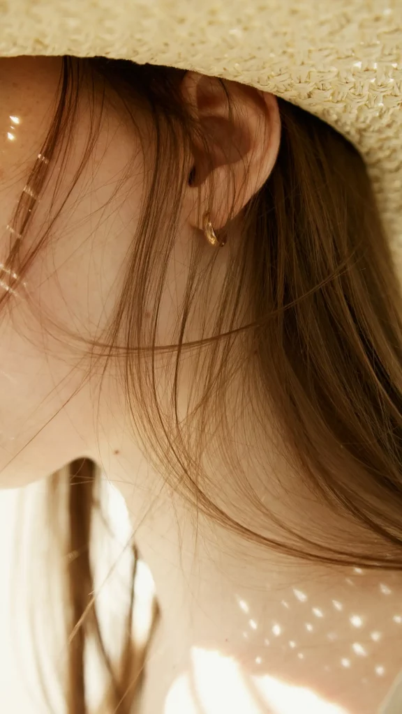 Photo macro représentant le profil d'une femme aux cheveux longs, portant un chapeau de paille